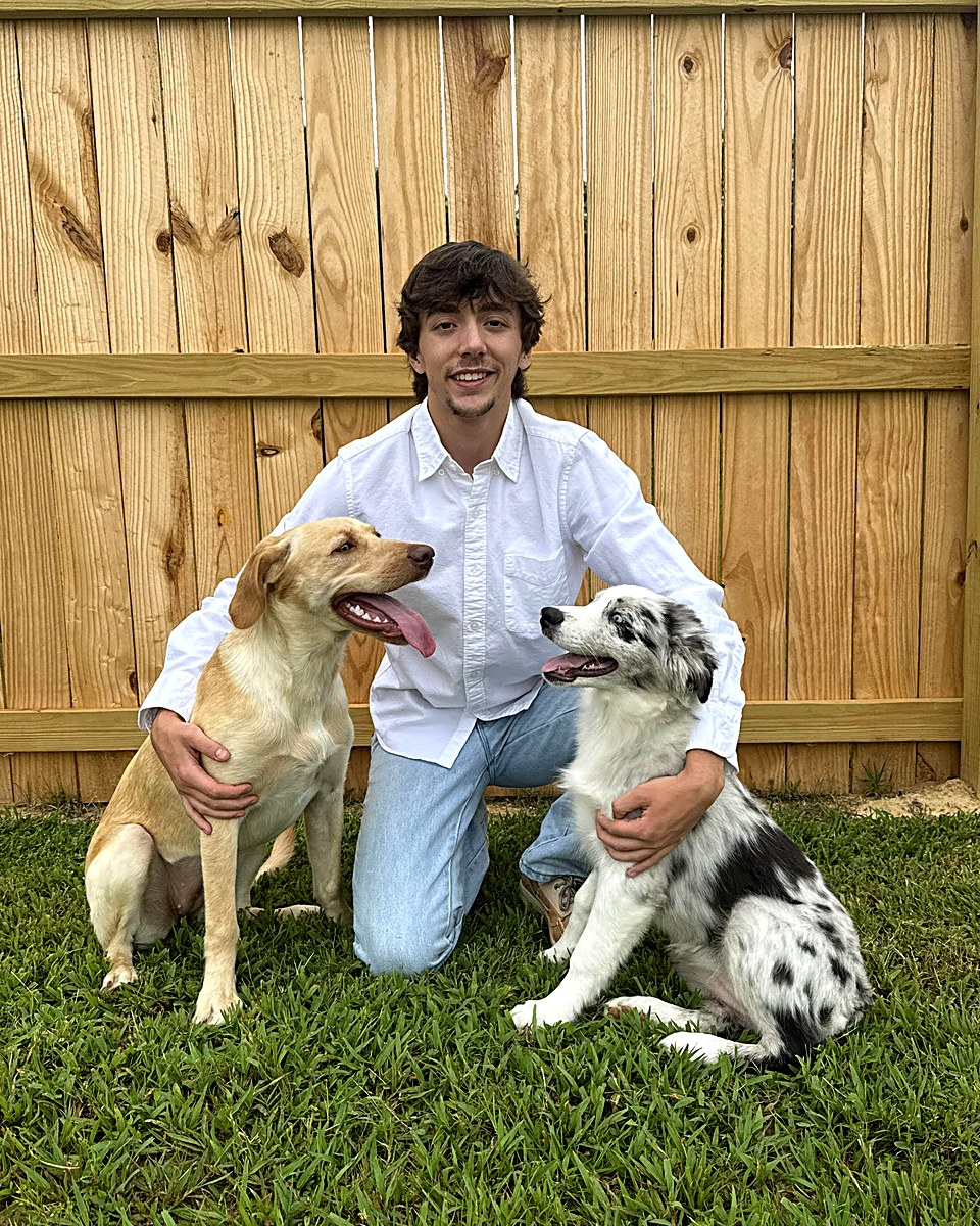 Dakota, founder of ApexSites, kneeling with his two dogs