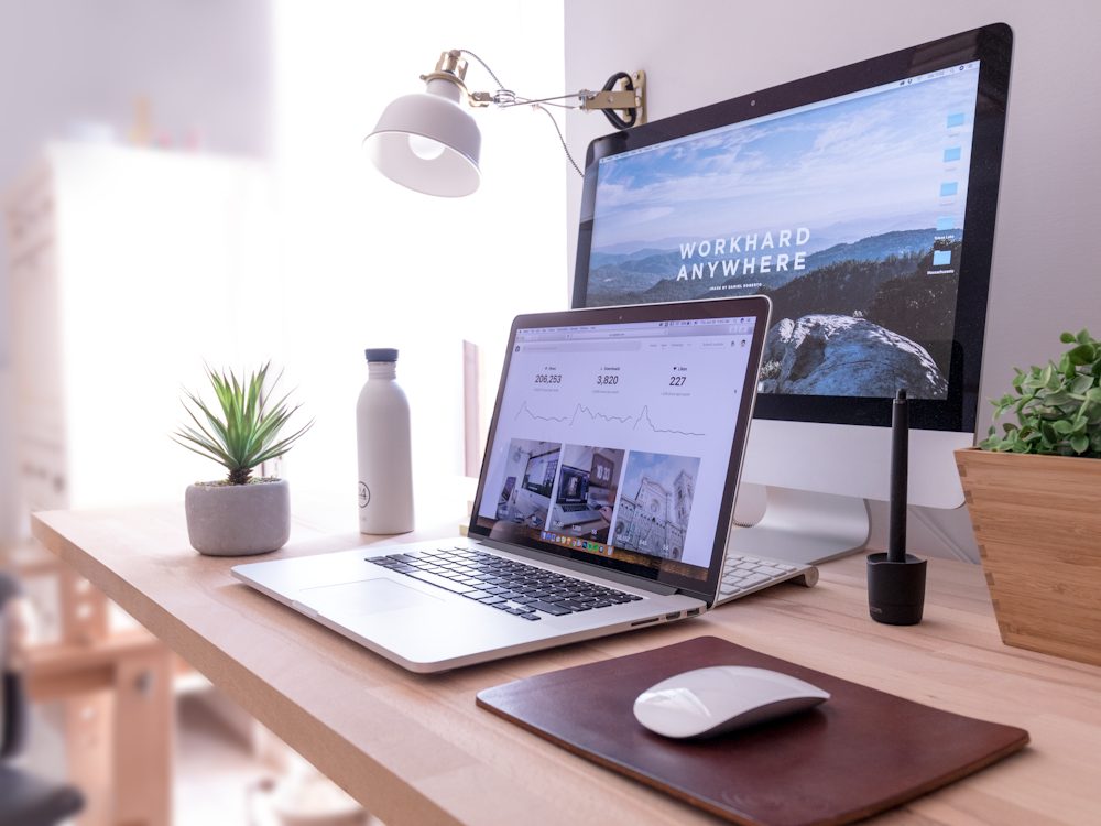 A clean, modern designer workspace with a laptop showing a website design